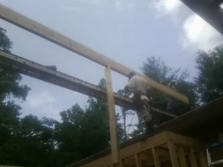 Carpenter setting a ridge beam over a new addition frame — Ice Dam Removal by Roofing Brothers in State Road