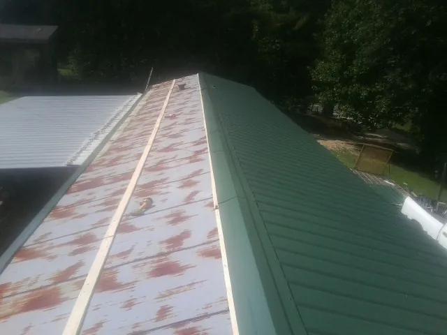 Old rusted panels beside newly installed green metal roofing — Wind Damage Roof Repair by Roofing Brothers in State Road
