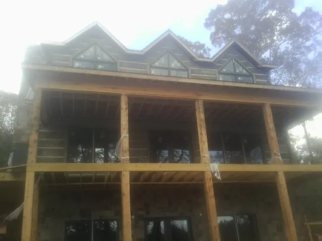 Dormers and porch framing on a large log home under construction — Roof Coating work by our crew in State Road
