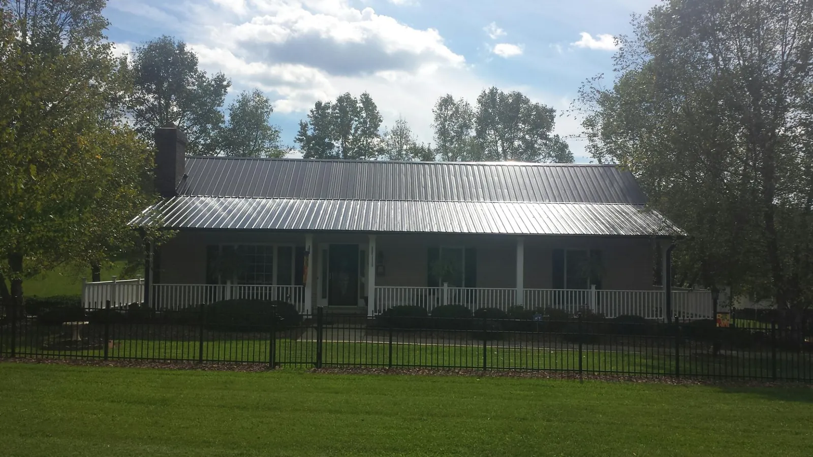 Gray metal roof on a brick ranch with a full width front porch — Gutter Guard Installation work by our crew in State Road