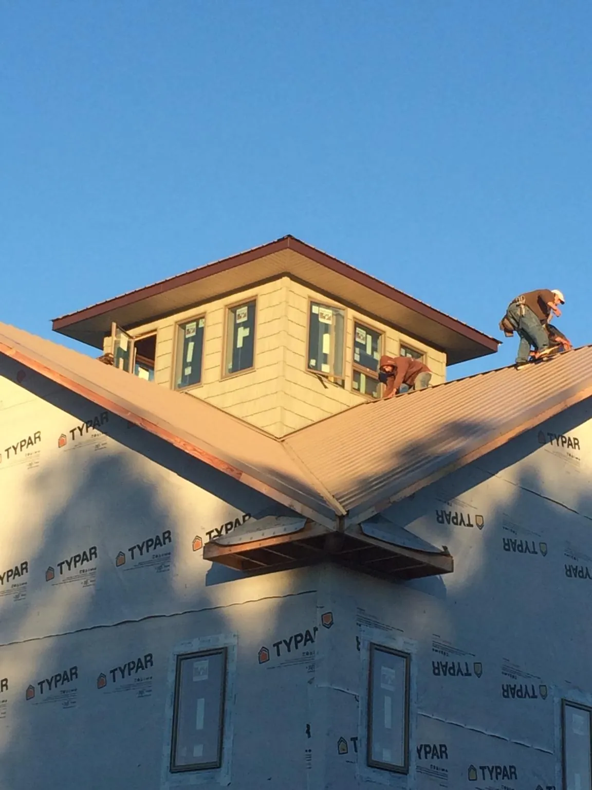 Roofers working around a rooftop cupola on a new metal roof at sunset — Roof Waterproofing in State Road by Roofing Brothers